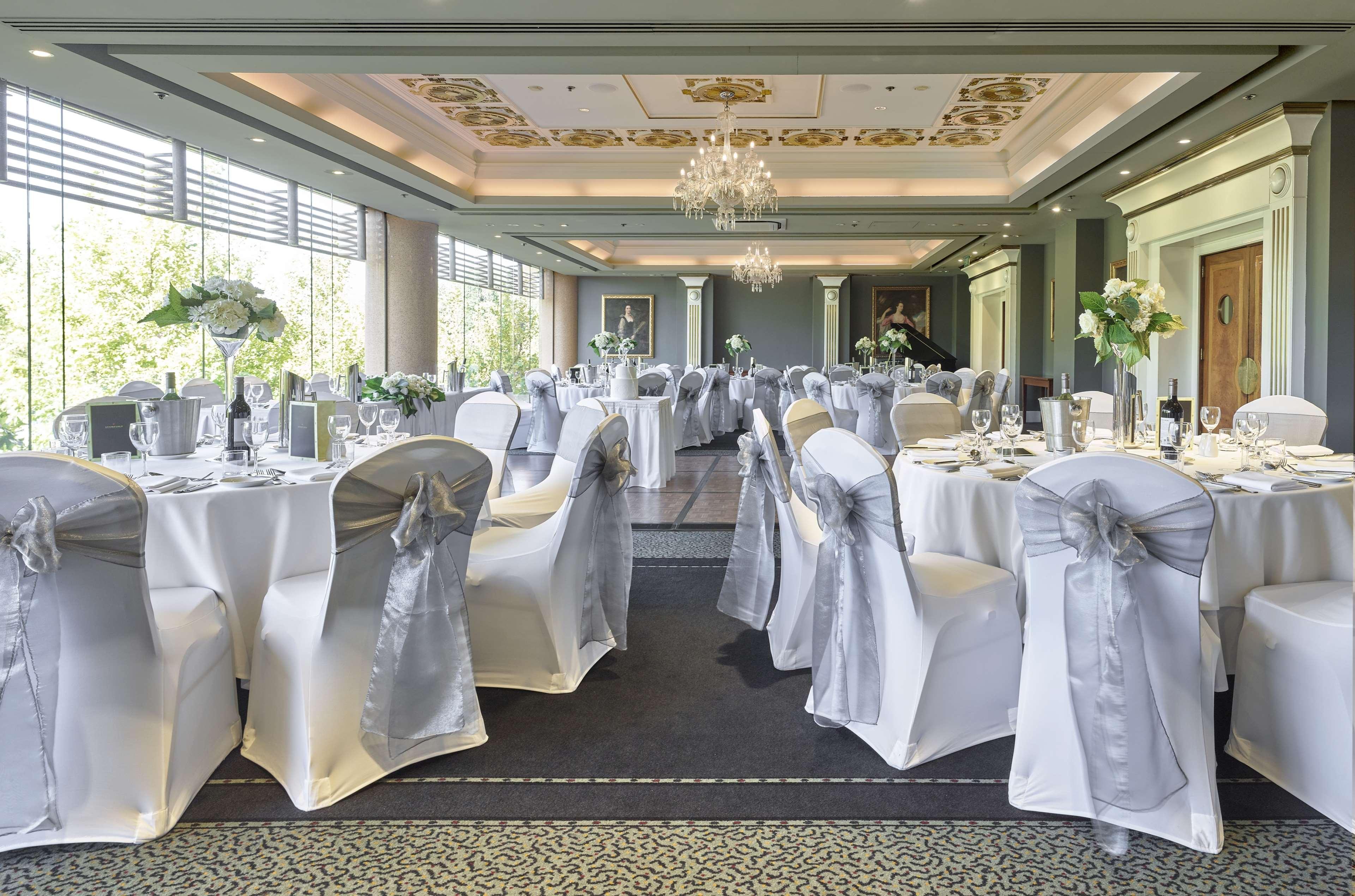 Stamford Plaza Adelaide Hotel Luaran gambar The photo displays an elegantly arranged banquet hall. The room features several round tables covered with white tablecloths, each adorned with silver sashes on the chairs. There are floral centerpieces, possibly white flowers, on the tables, adding 